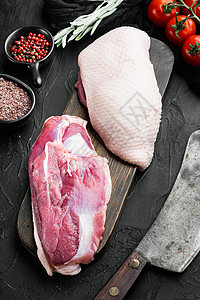 新鲜鸭肉作为食物 生鸭乳用老屠宰刀 黑色石块背景 顶视板铺平背景图片