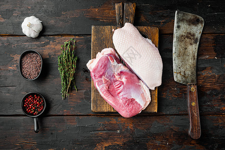 生的未煮过的禽肉被切开 鸭胸 在木切板上 用旧的切肉刀 在旧的深色木桌背景上 顶视图平躺背景