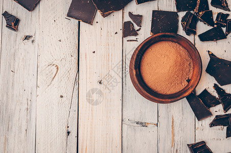 不含糖和麸质的黑巧克力适合糖尿病患者和过敏者 右边的碗里放着几块带有面包屑和可可粉的巧克力 健康饮食的概念 复制空间背景图片