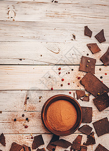 浅色粉末背景不含糖和麸质的黑巧克力适合糖尿病患者和过敏者 巧克力片撒上可可粉 面包屑 黑胡椒和红胡椒粉 右侧带有浅色 复制空间背景