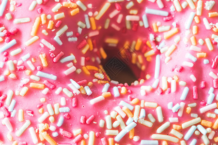 糖喷洒的粉红色甜甜甜圈带 贴近画面生活方式甜点糖链面包庆典享受糖霜食物蛋糕味道背景