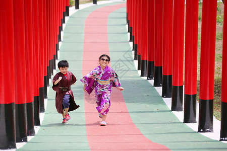 赏荷孩子两个和服里的小孩 走进圣殿红门 在日本花园里旅行女士艺妓小路女孩神道寺庙隧道建筑学裙子背景