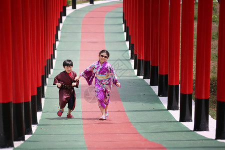 赏荷孩子两个和服里的小孩 走进圣殿红门 在日本花园里女孩裙子神道传统隧道宗教旅行戏服艺妓地标背景