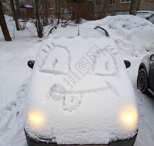 一辆被雪覆盖的汽车 引擎盖上有一张滑稽的脸 冬府高清图片
