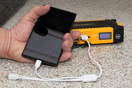 小工具成瘾手持黑色智能手机从 powerban 充电背景