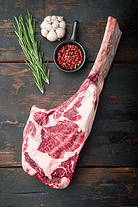 牛排和牛排 生鲜大理石牛肉 配有调味料和草药 在旧的黑暗木制桌底背景上图片