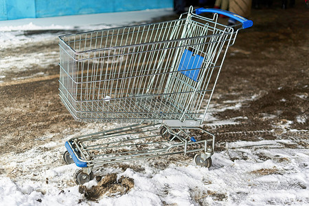 雪中的小车来自超市的金属购物小车 在户外雪和泥土中站立背景
