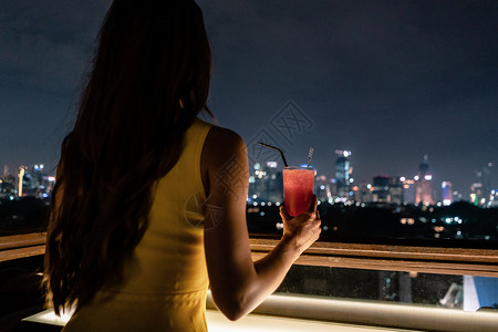 女人在屋顶露台喝着酒 俯视城市派对酒吧夜生活女士景观建筑学背景图片