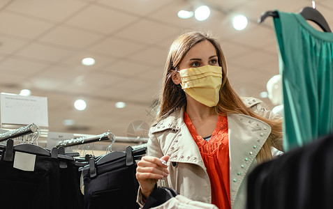 穿着面罩在时装店购物的妇女店铺百货安全危机衣服商店面具女士口罩肺炎背景图片