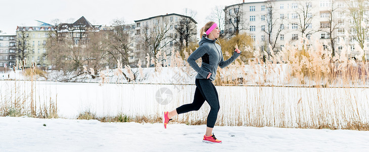 慢跑鞋妇女冬季在公寓楼门前参加体育运动活动(女子)背景