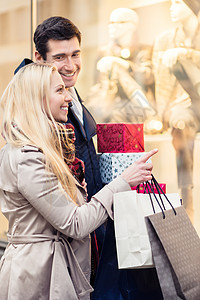 城里有圣诞礼物的男男女女店铺购物橱窗男朋友夫妻男人礼物女朋友城市零售背景图片