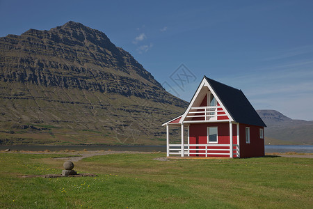 在冰岛东部爱斯基菲约尔杜尔背景中拥有强大的Holmatindur山的传统红漆木板房吸引力海岸村庄支撑海岸线蓝色冰川地标海洋旅行背景图片