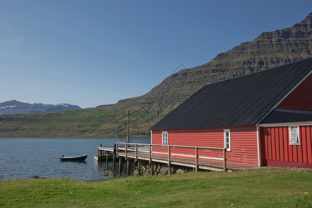 在冰岛东部爱斯基菲约尔杜尔背景中拥有强大的Holmatindur山的传统红漆木板房地标海岸旅游冒险风景环境蓝色建筑支撑农村背景