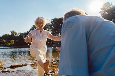 在阳光明媚的夏日 在河边玩水的情侣女性高清图片素材