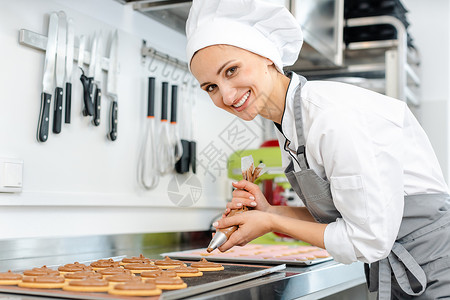 收信员女人用糕饼包 在饼干上加奶油甜点传统工作作坊糕点师糖果蛋糕店铺生产烘烤背景