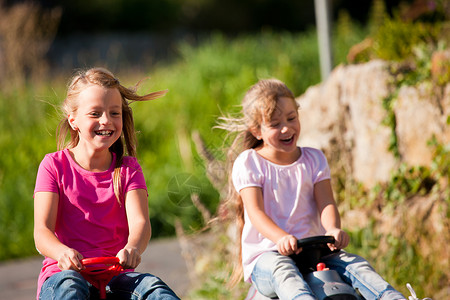 两个姐妹带着玩具车爬坡乐趣竞赛行动兄弟姐妹享受快乐赛车孩子驾驶背景图片