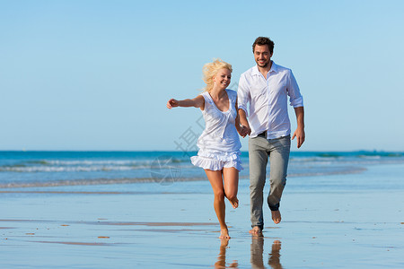 海滩上的情侣奔向辉煌的未来男人快乐假期乐趣阳光照射自由妻子沙滩闲暇成人背景图片