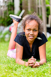 黑女孩躺在草地上的草刀上姐姐移民刀刃女孩黑色院子花园背景图片