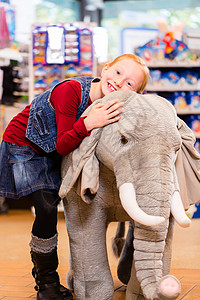 玩具店的小女孩和充装动物抱在一起店铺零售毛绒女孩孩子填充购物女儿玩具毛绒玩具高清图片素材