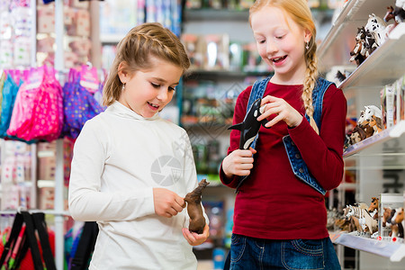 两个小孩在玩具店买玩具玩具零售姐妹店铺购物孩子们女孩们乐趣女儿们公仔快乐的高清图片素材