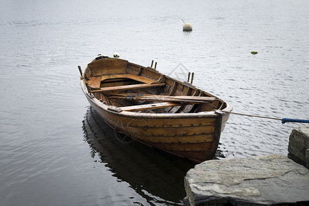赫米瓜在一个码头附近湖面的一艘船 日落在村里湖上 从木桥和另一条船旁看到蓝色旅游岩石旅行公园木船钓鱼反射游客高山背景