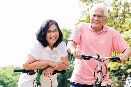 活跃的老年夫妇在自行车上站立的肖像退休公园棉布活力机动性植被爱好夫妻牙齿微笑妻子高清图片素材