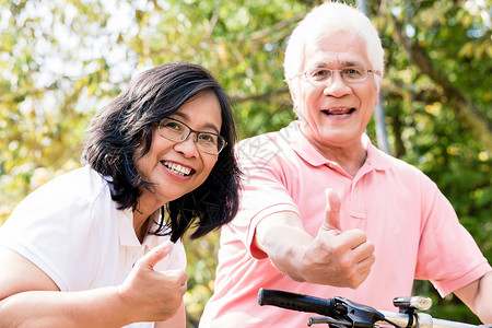 活跃的老年夫妇在自行车上站立的肖像微笑灵活性机动性牙齿活力男性公园棉布女性活动户外高清图片素材
