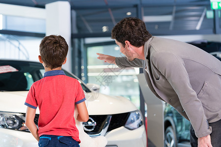 父亲和儿子在汽车经销商展厅买车男人孩子们顾客后代男生家用车陈列室爸爸代理商背景图片