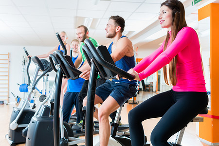 体操中骑心型自行车的男女活动体育锻炼纺纱俱乐部伙伴动机康复运动女性工作室背景图片