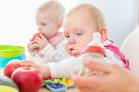 在现代日托中心食用健康固体食品的可爱女婴高清图片