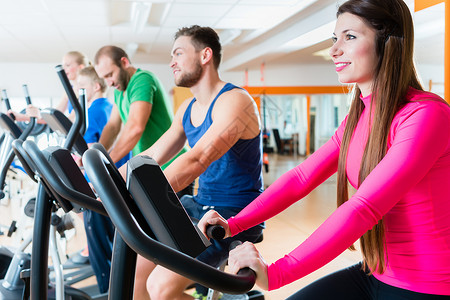 体操中骑心型自行车的男女运动员理疗师俱乐部女士工作室伙伴纺纱动机健身房运动背景图片