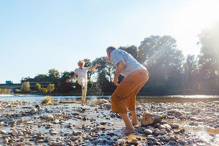 有趣的老年情侣在阳光明媚的河边玩水户外高清图片素材