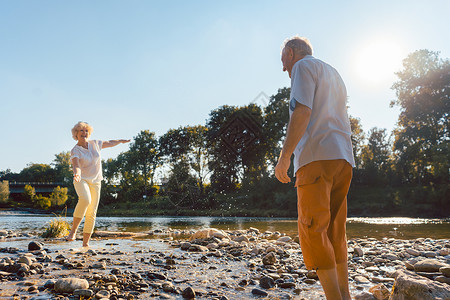 在阳光明媚的天气下 在河边玩水的 有趣的老年情侣赤脚岩石享受机动性女性晴天男性夫妻长老福利老的高清图片素材