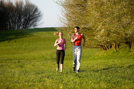 为户外运动而慢跑的情侣草地活动娱乐训练运动闲暇乐趣成人夫妻阳光背景图片