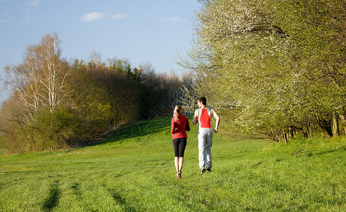 为户外运动而慢跑的情侣男人成人草地闲暇夫妻训练阳光乐趣娱乐女士背景图片