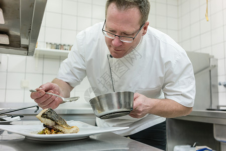 厨师在餐厅吃盘子鱼精加工食物酒店男人男性躯干烹饪厨房淡水白色背景图片