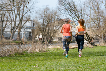 母亲和成年女儿沿河奔跑 参加体育活动晴天老年活力赛跑者喜悦远距离运动锻炼跑步慢跑者背景图片