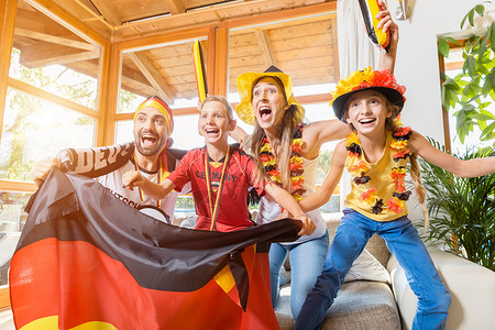 整个家庭都在电视前为德国足球队欢呼播送化妆品父亲孩子们比赛胜利父母母亲乐趣锦标赛背景图片