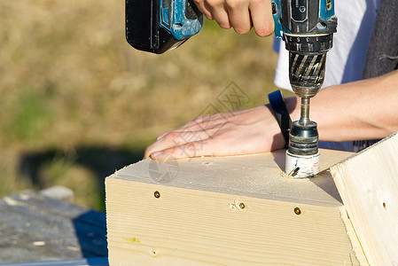 木头孔锯在鸟舍上钻一个洞 一位少爷做了一个鸟舍 用木刨机钻了一个洞组装木工安装建造作坊铣削钻孔男人维修乐器背景