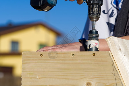 木头孔锯在鸟舍上钻一个洞 一位少爷做了一个鸟舍 用木刨机钻了一个洞铣削木工锯末组装机器工匠工作安装木匠建造背景