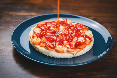把番茄酱放在披萨 香肠和螃蟹棒上高清图片