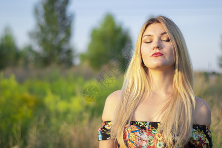 在田里穿着鲜花洋装的迷人金发美女 光亮闪亮的肖像农村长发草地花卉头发场地农田青少年自由女性背景图片