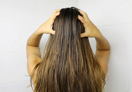 年轻女人用指头涂发油 洗头发前擦头发 理发概念背景图片