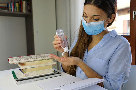 防疫知识宣讲2019-nCoV 家庭工作 自动隔热 防疫 卫生和保健概念 使用喷雾器的酒精胶液从家中进行外科面具研究的科罗纳大流行病毒妇女背景