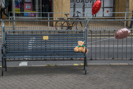 泰迪熊被留在路边的木椅上背景图片