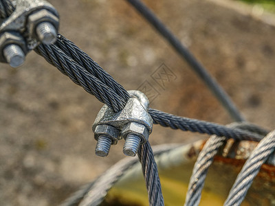 挂在电缆和安全网上的小缝隙金属螺栓力量编织缆绳索具钢丝绳曲线娱乐质感背景图片