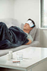 躺在沙发 身患寒冷和冬季流感病毒的病死老人有医疗护理概念中的药片 在温度计上观察温度流感白色围巾药品发烧疾病成人背景