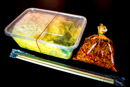 带酱汁的意大利面条 用塑料包装将食物带回家筷子托盘盒子美食红色背景图片