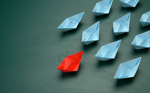 绿色背景的纸船小组 一个团队中的强力领导 操纵群众的概念 (掌权)背景图片