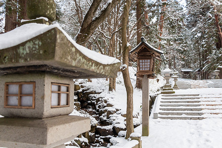 ps飞石素材日本石灯笼和木灯笼在冬季飞驒三宫 HieJinja 神社有雪 在岐阜 飞騨高山 日本季节公园建筑学木头三王入口建筑石头森林地标背景